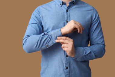 Kahverengi arka planda mavi yakalı genç bir adam.