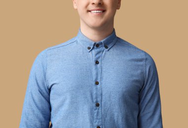 Kahverengi arka planda mavi yakalı genç bir adam.