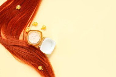 Sarı arka planda saç maskesiyle kırmızı iplik ve kapsüller.