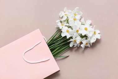 Bej arka planda nergis çiçekleri olan bir alışveriş çantası.