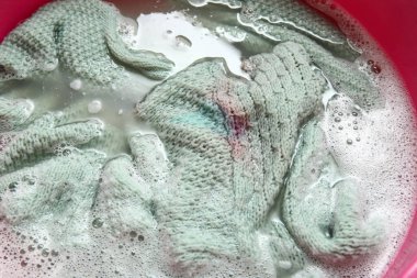 Kirli çamaşırları, köpüğü ve suyu olan plastik bir leğen.