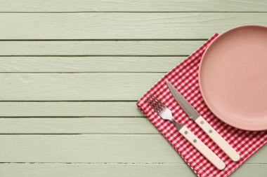 Tabak, çatal bıçak ve yeşil ahşap zemin üzerine peçete.