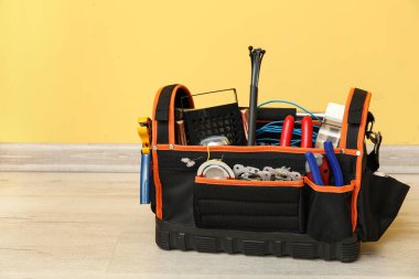 Sarı duvarın yanında yerde elektrikli alet çantası var.