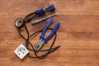 Elektrikçi aletleri, elektrik prizi ve ahşap arka planda kablo