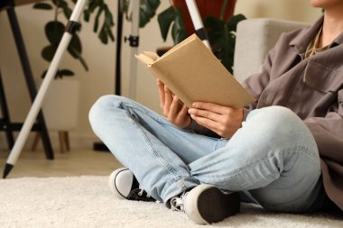 Evde yerde kitap okuyan bir ergen, yakın plan.
