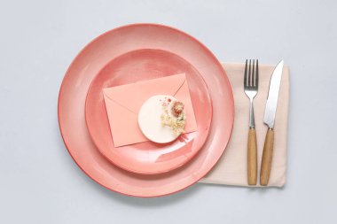 Gri arkaplan üzerinde güzel çiçekler ve zarf bulunan şık masa ayarları