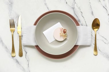 Altın çatal bıçak seti ve beyaz arka planda güzel çiçekler.