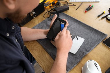 Servis merkezinde cep telefonunu tamir eden erkek teknisyen, yakın plan.