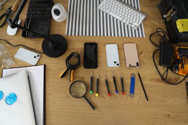 Servis merkezinde tamir aletleri olan kırık cep telefonları, üst görünüm