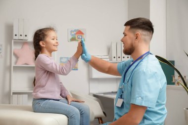 Küçük tatlı kızı olan bir erkek çocuk doktoru klinikte beşlik çakıyor.