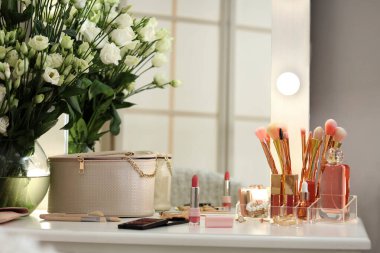 Dekoratif kozmetik ürünleri ve vazo. Soyunma odasındaki masada çiçekler.