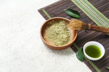 Beyaz arka planda chasen ile bir kase kibrit çayı ve pudra.