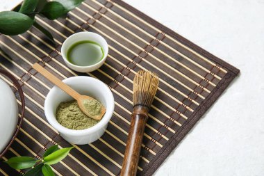 Beyaz arka planda chasen ile bir kase kibrit çayı ve pudra.