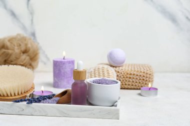 Lavanta yağı, masaj vücut fırçası ve fayans zemininde deniz tuzu olan güzel bir kompozisyon.