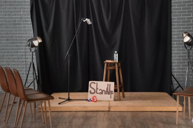 Mikrofonlu stand-up sahnesi, parlayan lambalar ve sandalyeler