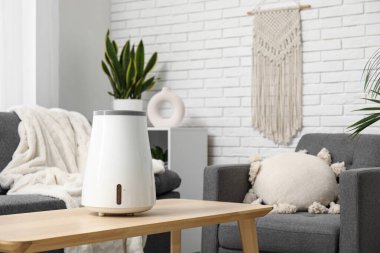 Oturma odasındaki siyah kanepenin yanındaki kahve masasında modern nemlendirici.