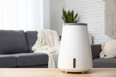 Oturma odasındaki siyah kanepenin yanındaki sehpanın üzerinde modern nemlendirici var.