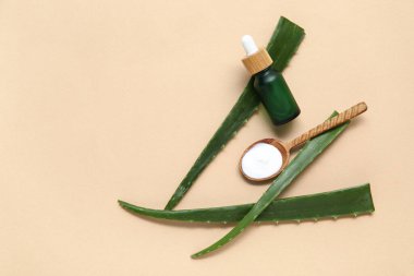 Esaslı yağlı taze aloe yaprakları ve bej arka planda yüz kremi ile kepçeyle.