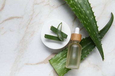 Yağ ve alçı dolu taze aloe yaprakları mermer arka planda duruyor, yakın plan.