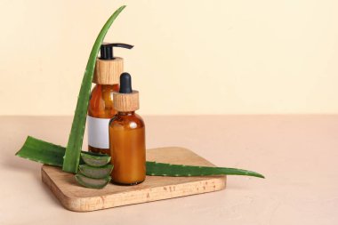 Ahşap tepsi ve bir şişe aloe vera esaslı yağ bej arka planda.