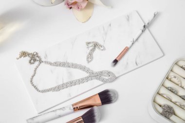 Giysi dolabında makyaj fırçası olan farklı mücevherler, yakın plan.