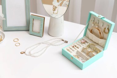 Masada farklı mücevherler, ayna ve fotoğraf çerçeveleri olan bir kutu, yakın plan.