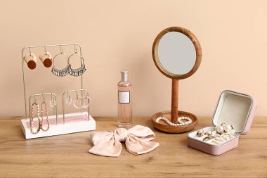Bej duvarın yanındaki dolapta farklı mücevherler, ayna ve parfüm şişesi olan organizatörler.