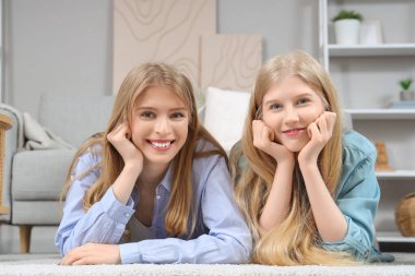 Güzel, genç, mutlu kız kardeşler evde yerde yatıyor.