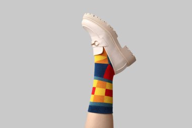 Çoraplı genç kadın bacağı ve beyaz arka planda ayakkabılar.