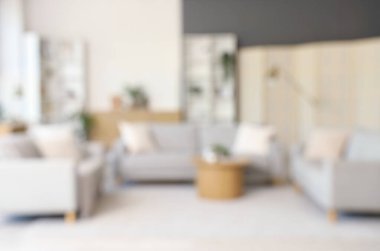 Gri kanepeler, kahve masası ve bitkilerle aydınlık oturma odasının bulanık görüntüsü