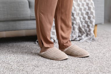 Oturma odasında rahat terlikler içinde kadın bacakları.