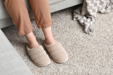 Oturma odasında rahat terlikler içinde kadın bacakları.