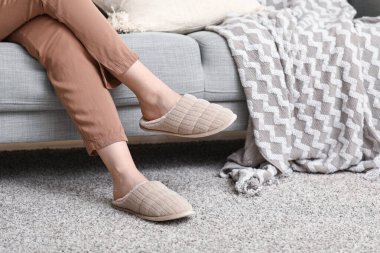 Oturma odasında rahat terlikler içinde kadın bacakları.