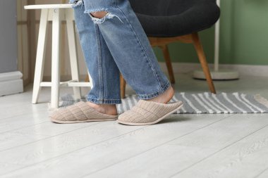 Kadın bacakları şık terliklerle odada, yakın plan.