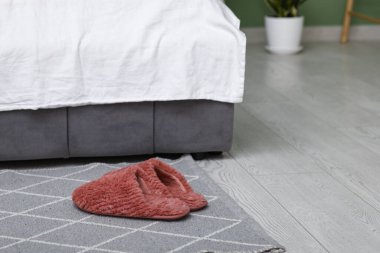 Yatak odasının yanında kırmızı terlikler.