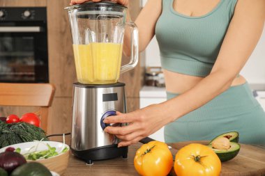Blendırlı sportif olgun kadın mutfakta smoothie yapıyor, yakın plan.