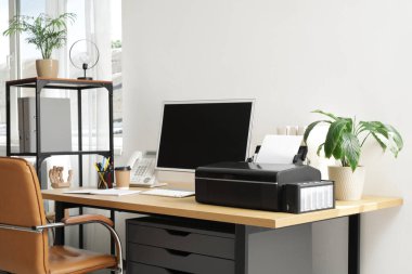 Ofis duvarının yanında bilgisayar ve yazıcılı modern işyeri