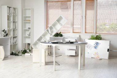 Depremden sonra mobilyaların ve ev bitkilerinin devrildiği dağınık ofis.