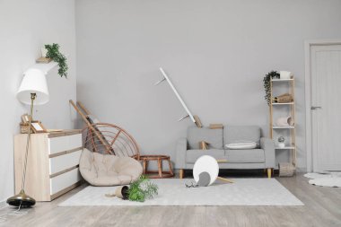 Depremden sonra mobilyaların ve çiçeklerin devrildiği dağınık oturma odasının içinde.