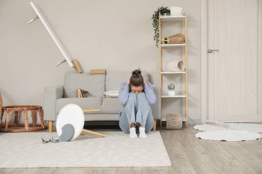 Deprem sırasında korkmuş genç bir kadın oturma odasında.