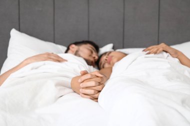 Evde el ele tutuşan uyuyan genç çift, yakın plan.
