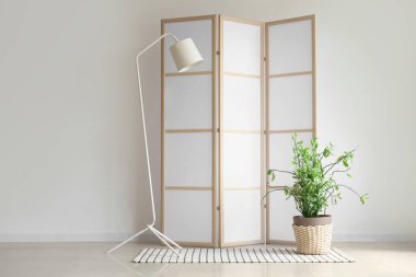 Işık duvarının yanında lamba ve bitki ile katlanır ekran