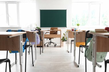 Masaları ve tahtası olan boş sınıfın içi
