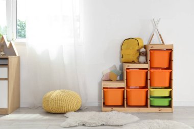 Sınıfta rafta oyuncak olan sarı sırt çantası.