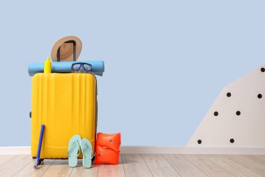 Mavi duvarın yanında toplanmış bavullar ve plaj aksesuarları.
