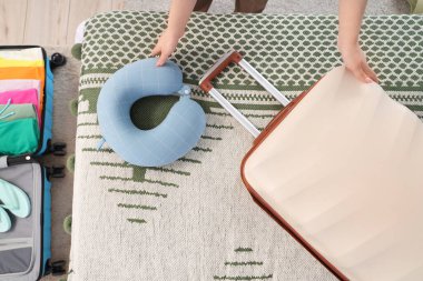 Yatak odasında, bavulun yanında boyun yastığı olan bir kadın. Seyahat konsepti. Üst görünüm