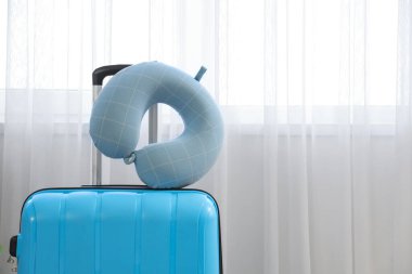 Bavuldaki boyun yastığı ışık perdesinin yanında. Seyahat kavramı