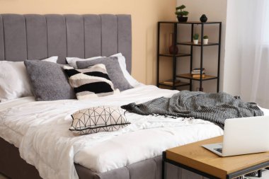 Rahat yataklı modern yatak odası, dizüstü bilgisayarı ve raf ünitesi olan bank.