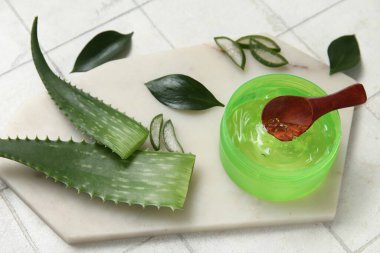 Bir kavanoz aloe vera jeli ve beyaz karo arka planda yaprakları ile pano