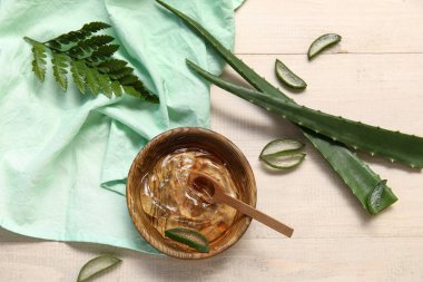 Bir kase aloe vera jeli ve beyaz ahşap arka planda yapraklar